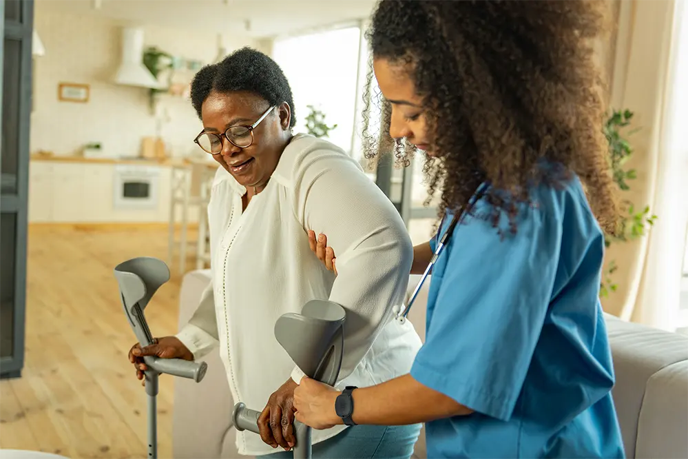 Nurse walking an elderly lady, while a Silent Beacon is on the nurses hand.