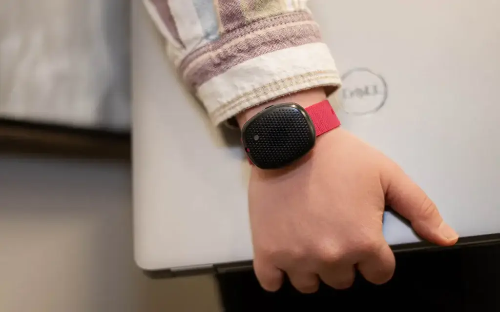 Woman wearing a wireless silent panic button for office while holding her laptop.