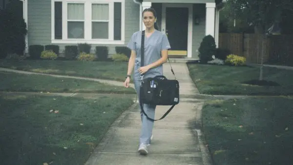 Home healthcare worker wearing a Silent Beacon panic button while providing care to a patient in a residential setting.