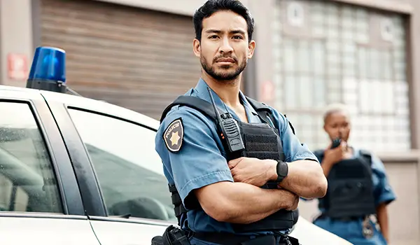 Asian police officer wearing a Silent Beacon panic button while serving in a law enforcement role.